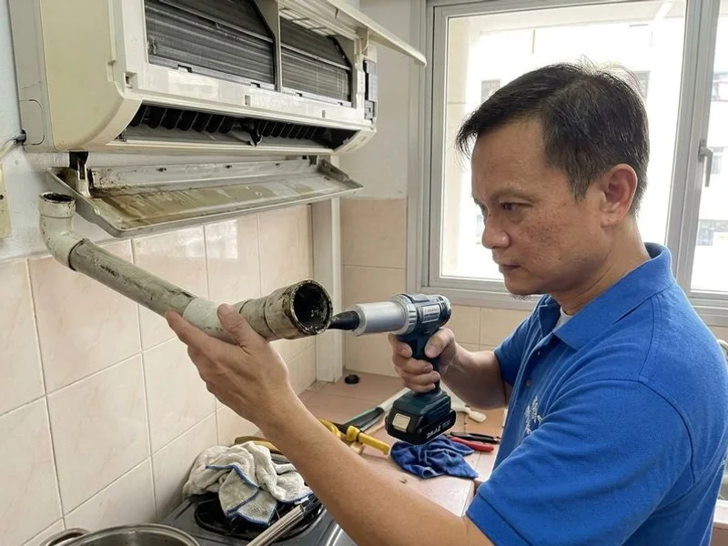Billy Aircon technician using a vacuum pump to clear a clogged condensate drain pipe