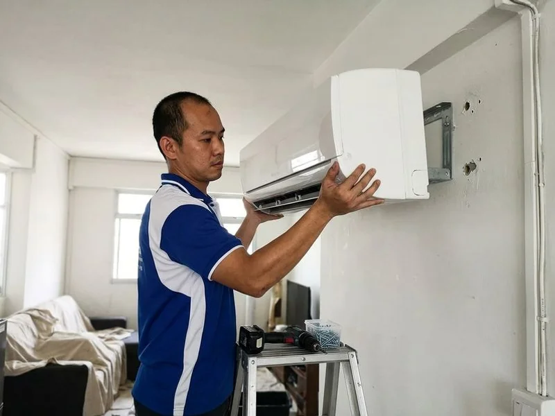 Billy Aircon technician mounting an indoor split unit on a wall bracket in a new HDB flat